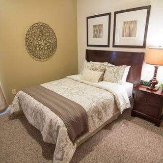 A cozy bedroom with a neatly arranged bed, nightstand, and decorative artwork.
