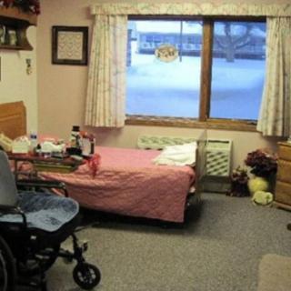A cozy bedroom with a single bed and a wheelchair near the window.