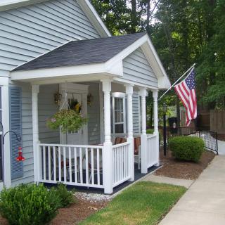 A charming suburban house with a small porch and an American flag displayed.