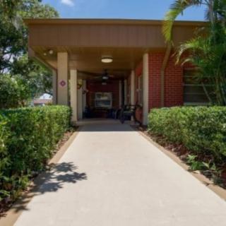 A building entrance surrounded by neatly landscaped plants and a clear pathway on a sunny day.