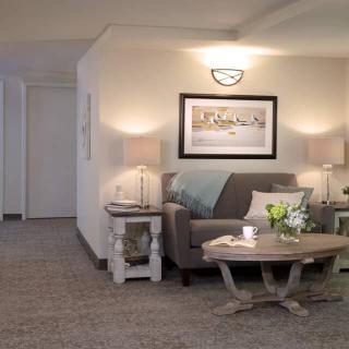 A cozy living room with a sofa, coffee table, lamps, and wall artwork.