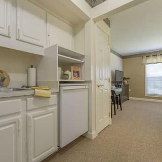 A small kitchen area opens into a cozy living room with a window.