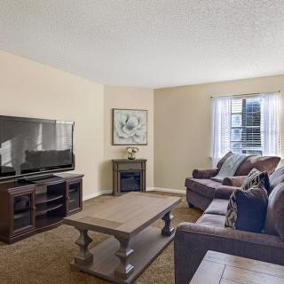 A cozy living room with a large television, comfortable sofas, and a wooden coffee table.