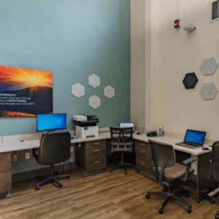 A modern office space with multiple workstations equipped with computers and a printer.