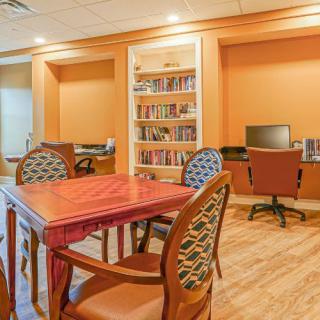Cozy study room with a wooden table, chairs, bookshelves, and a computer station.