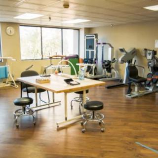 A rehabilitation room equipped with various exercise machines and therapy tables.