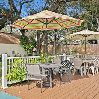 Outdoor patio area with tables, chairs, and umbrellas on a wooden deck.