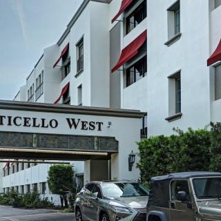 The entrance of Monticello West with red awnings and parked cars in front.