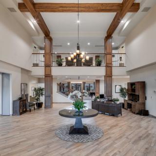 A spacious and modern lobby featuring wood beams, a chandelier, and elegant furnishings.