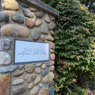 A beautifully crafted stone wall with a sign, surrounded by lush greenery.