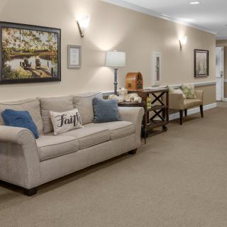 A cozy living room with a beige sofa, decorative cushions, and artwork on the wall.