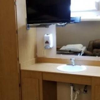 A bathroom sink area with a wall-mounted TV and a cabinet.