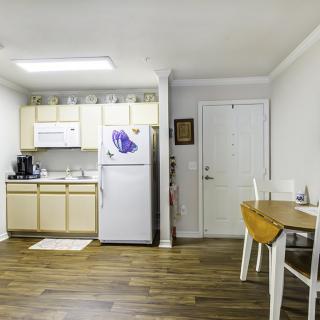 A compact apartment kitchen with a dining area, featuring light wood flooring and modern appliances.