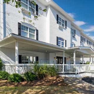 A beautiful residential building featuring a white facade and a welcoming porch under a clear blue sky.
