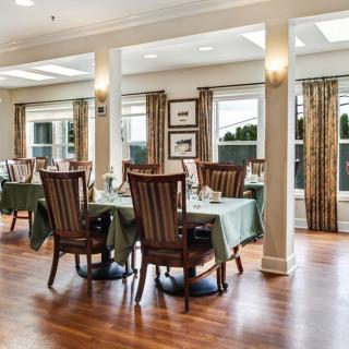 An elegant dining area with wooden flooring and well-arranged tables and chairs.
