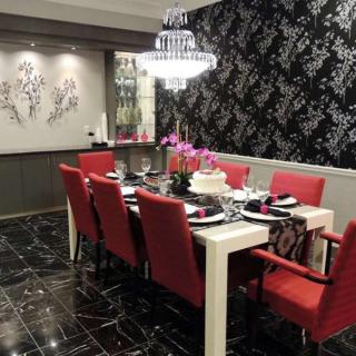 A modern dining room with elegant red chairs and a stylish chandelier.