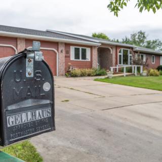 A suburban house with a mailbox in the foreground and a driveway leading up to it.