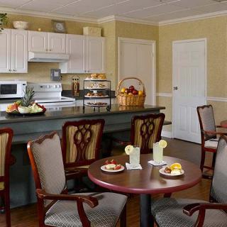 A cozy kitchen and dining area with tables set, chairs, and kitchen appliances.