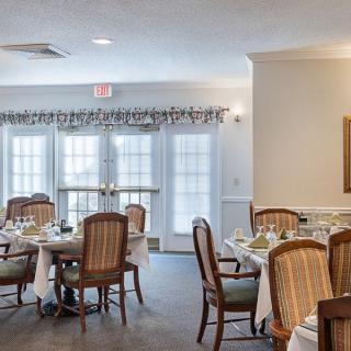 An elegant dining room setup with multiple tables and chairs, featuring large windows and tasteful decor.