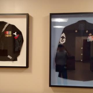 Framed military uniforms displayed on a wall, showcasing historical attire.