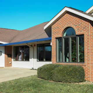 A charming brick house with large windows and a well-maintained front yard.