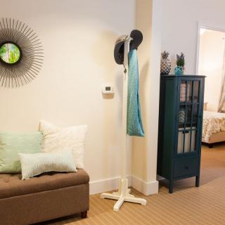 A cozy living room with a modern coat rack, stylish cushions, and decorative artwork on the wall.