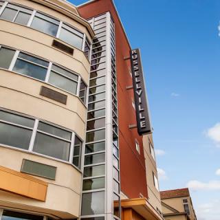 A modern urban building with a prominent sign against a clear blue sky.