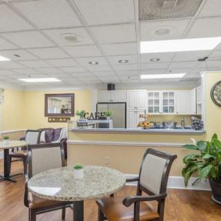 A cozy dining area with tables, chairs, and a view of the kitchen.