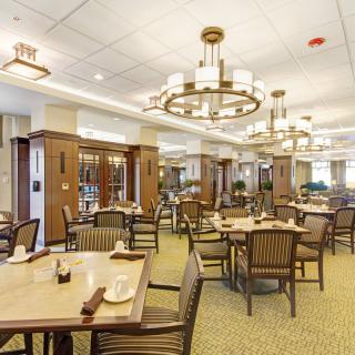 Spacious dining room with elegant chandeliers and well-arranged tables and chairs.