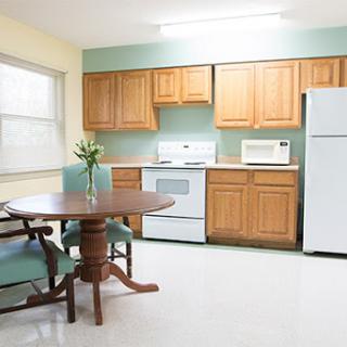 A cozy kitchen featuring wooden cabinets, a dining table, and essential appliances.