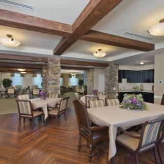 A spacious dining area with elegant tables and chairs, featuring wooden beams and stone columns.