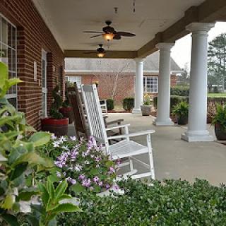 A peaceful porch with rocking chairs surrounded by vibrant greenery.
