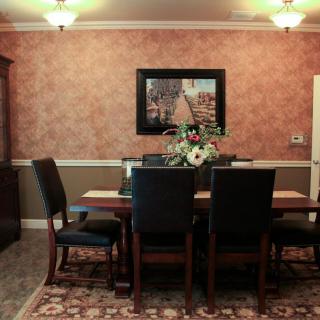 A cozy dining room featuring a dark wooden table with black chairs, enhanced by wall art and a floral centerpiece.