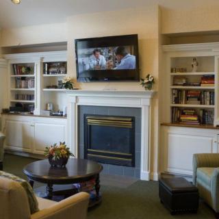 A cozy living room featuring a fireplace with a mounted television and built-in bookshelves.