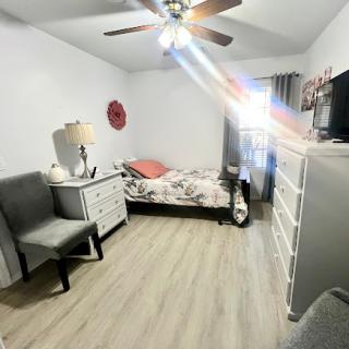 A cozy and well-lit bedroom featuring a bed, dresser, and comfortable chair.