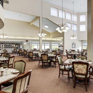 A spacious and elegant dining room with neatly arranged tables and chairs, illuminated by modern light fixtures.