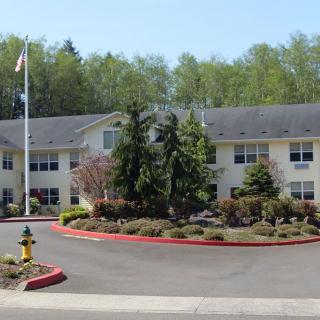 A residential building with a landscaped driveway and flagpole in front.