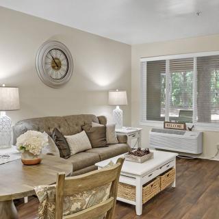 A cozy living room with a sofa, coffee table, and decorative elements including a wall clock and lamps.
