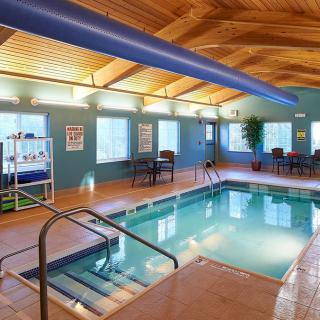 An inviting indoor swimming pool area with seating and a wooden ceiling.
