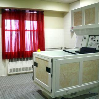 A room with a bathtub and red curtains covering a window.