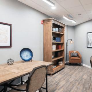 A modern office space with a wooden desk, bookshelf, and comfortable seating.