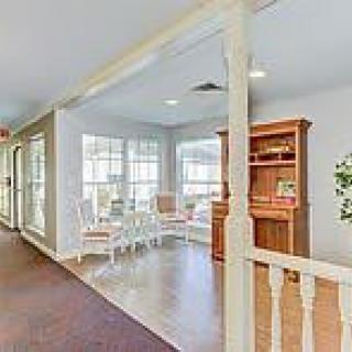 A cozy living space with large windows, featuring chairs and a wooden cabinet.