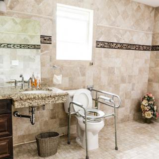 An accessible bathroom featuring tiled walls and necessary supports for convenience.