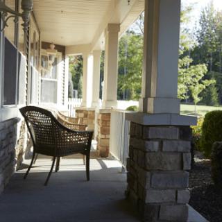 A cozy porch with a wicker chair, inviting relaxation in the morning sunlight.