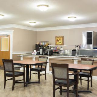 A cozy dining area featuring tables and chairs, accompanied by a coffee station in a well-lit space.