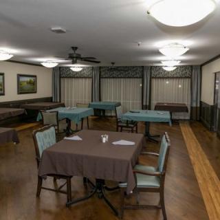 An empty dining room with neatly arranged tables and chairs, illuminated by ceiling lights.