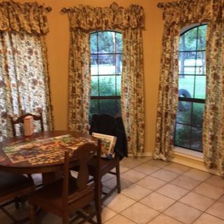 A cozy dining area with a round table and patterned curtains by the windows.