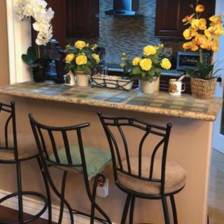 A cozy kitchen corner featuring a countertop with bar stools and vibrant floral decorations.