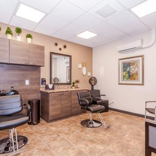 A modern and clean hair salon interior with chairs, a mirror, and stylish decor.