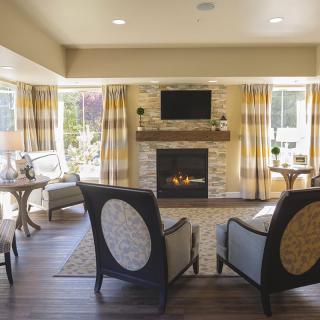 A modern living room with a fireplace and ample seating, featuring large windows that allow natural light to fill the space.